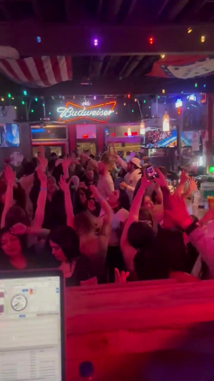 Packed crowd with hands up at Shots on Dickson Street, seen from the DJ booth