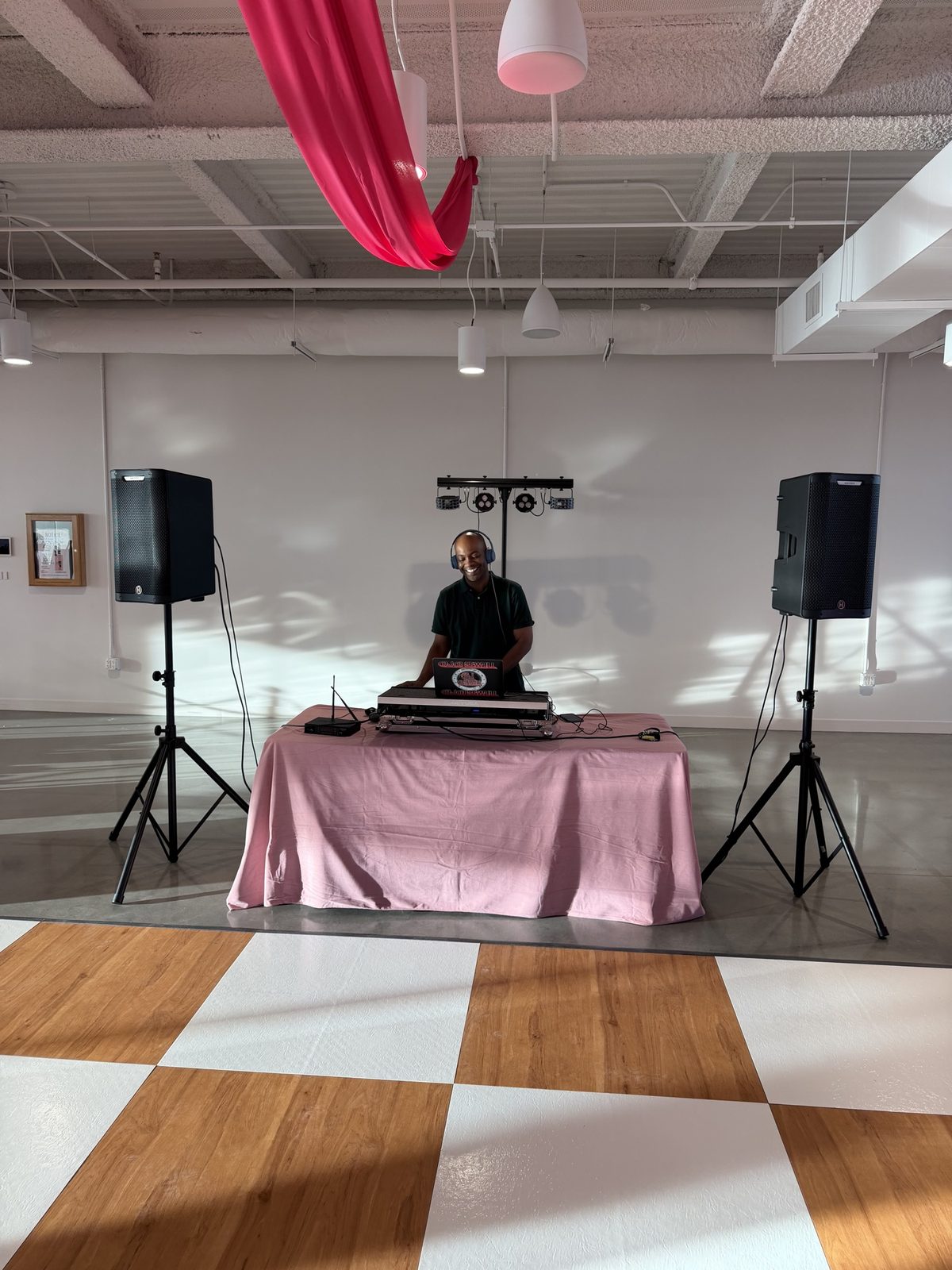 DJ D. Sewell smiling behind his booth at a wedding reception with a checkered dance floor